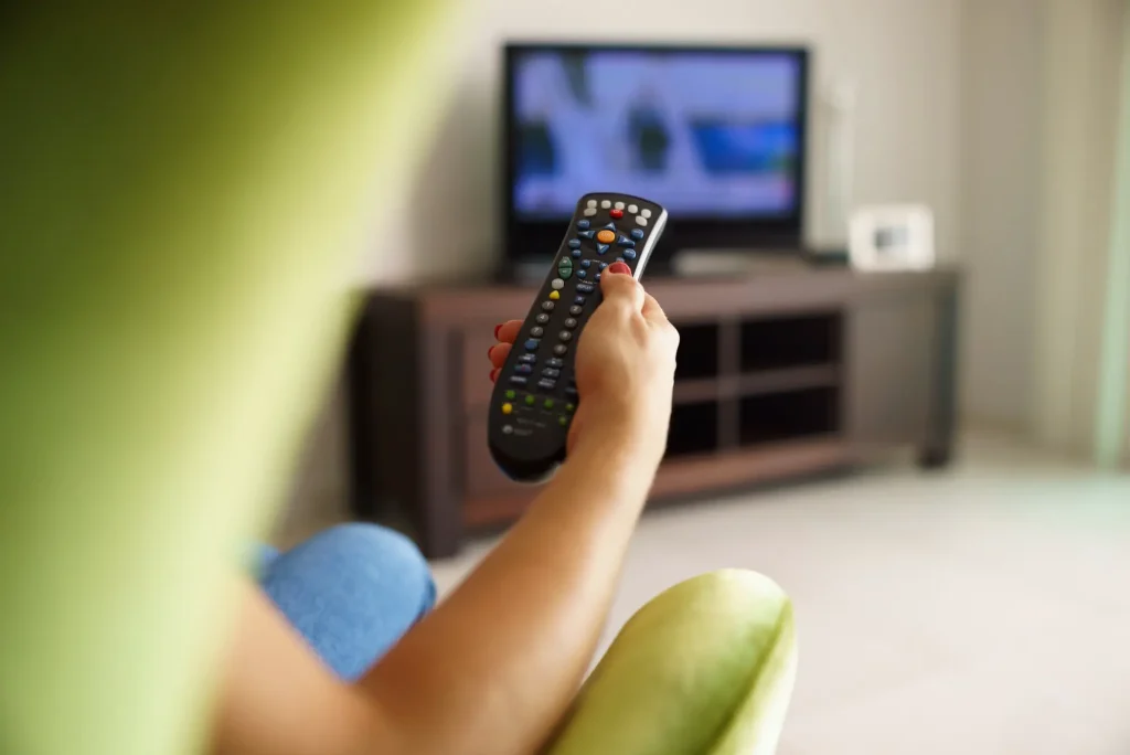 woman hand holding a tv remote watching tv