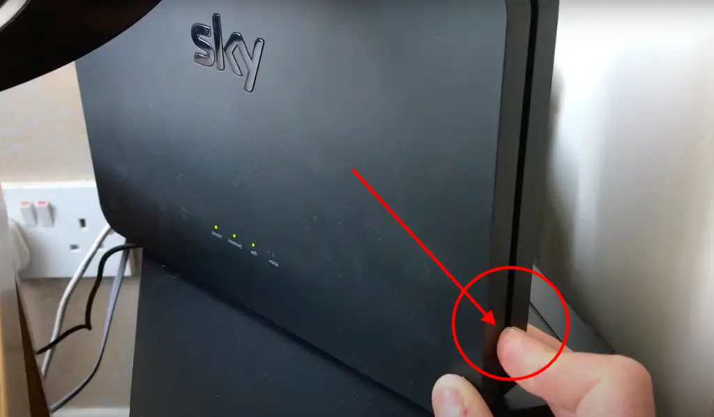Male hand pushing down wps button on sky broadband router