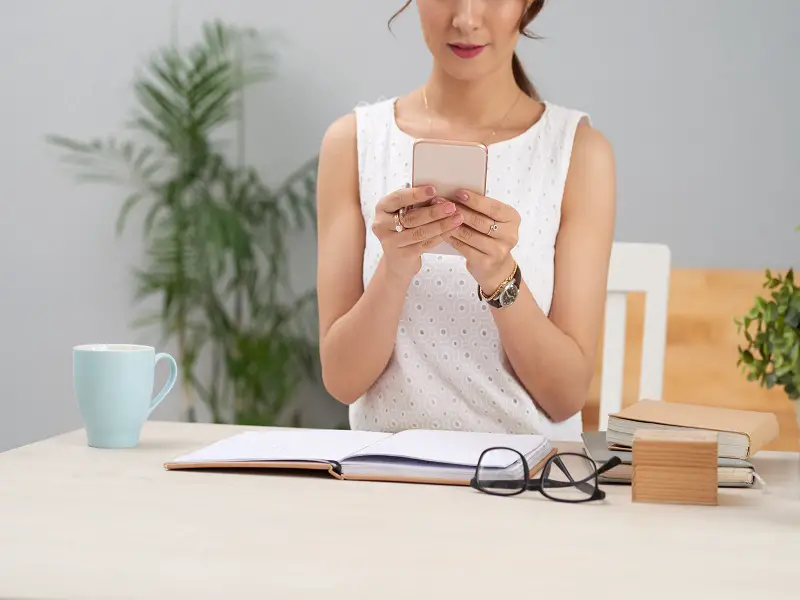 Business woman holding mobile phone in both hands