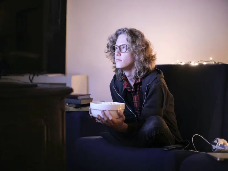 teenage boy watching tv with snacks