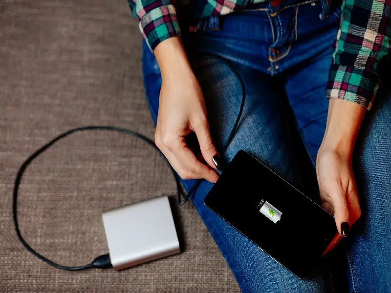 woman using power bank to charge phone