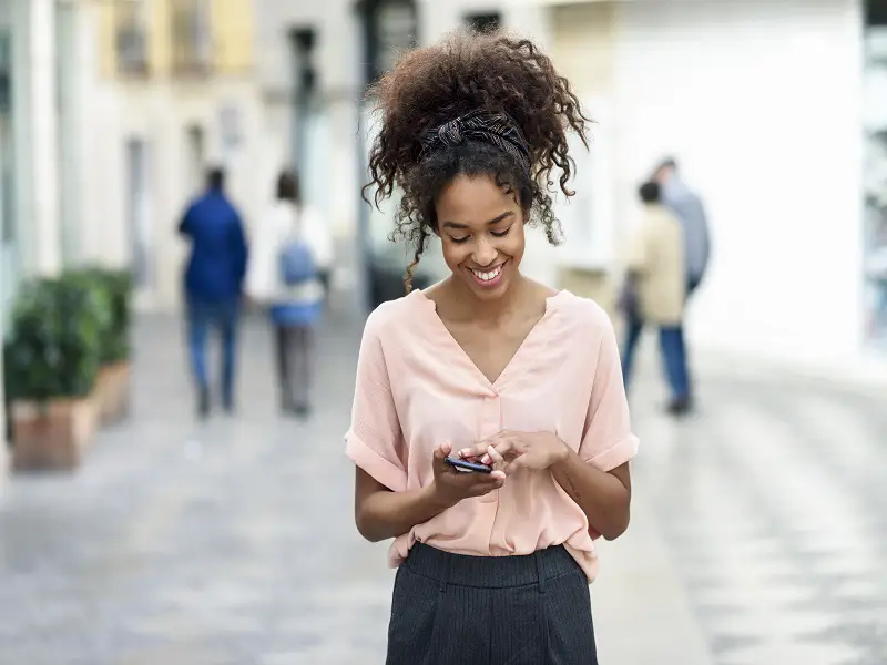 young woman smiling down at phone