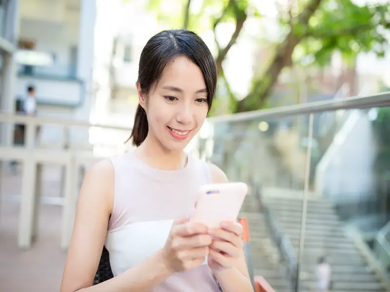 woman looking down at mobile phone smiling